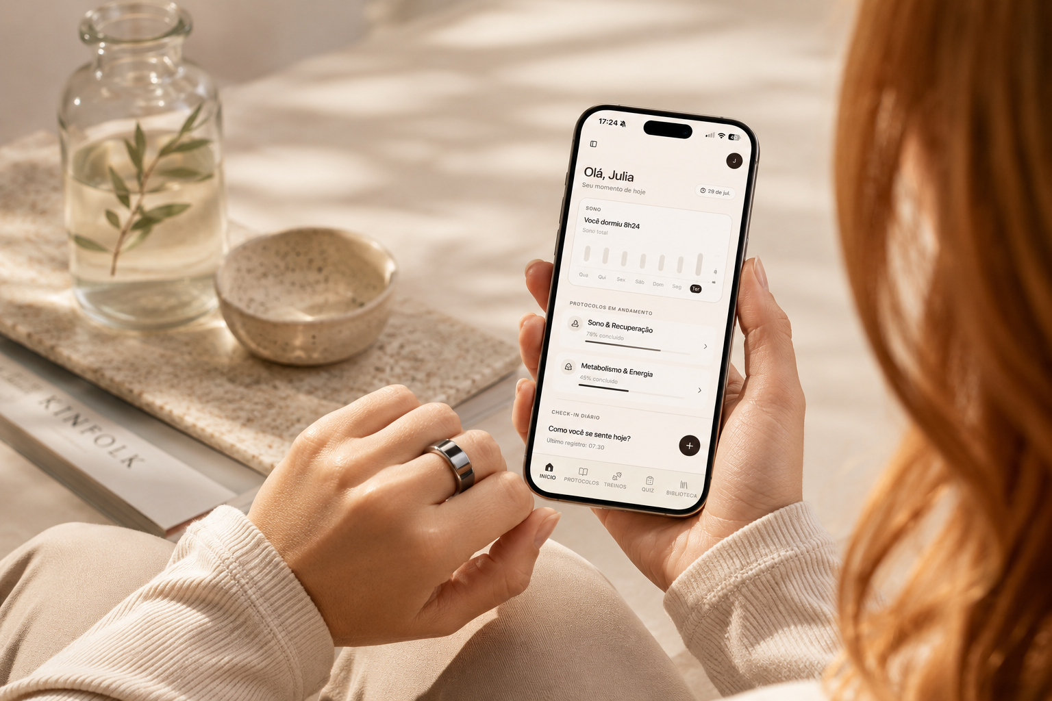 Mulher usando um anel inteligente prateado enquanto consulta o Julia Curcio Hub no iPhone